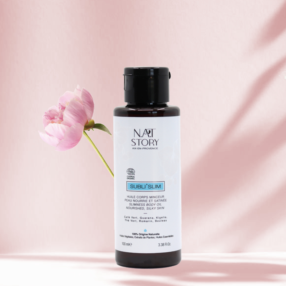 Flacon d'huile sur fond rose avec une fleur rose