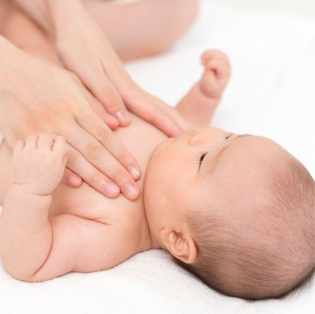 GROS PLAN SUR UN BÉBÉ AVEC LES MAINS DE SA MAMAN POSÉES SUR SA POITRINE